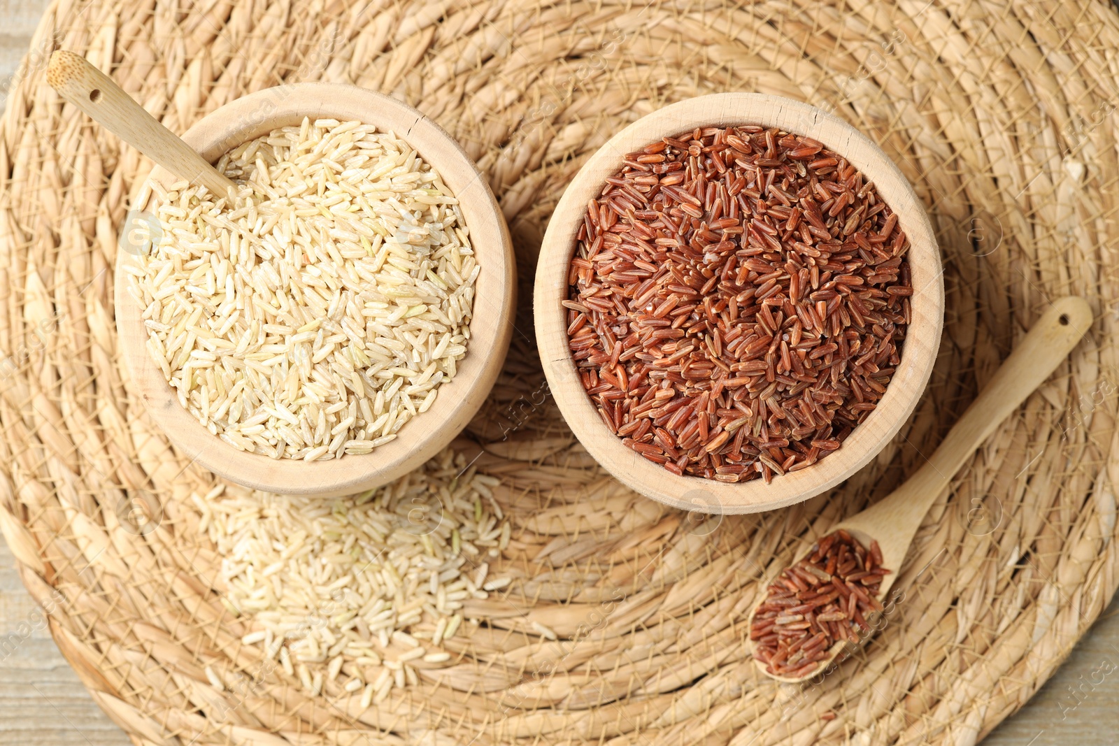 Photo of Different sorts of raw brown rice on wooden table, top view