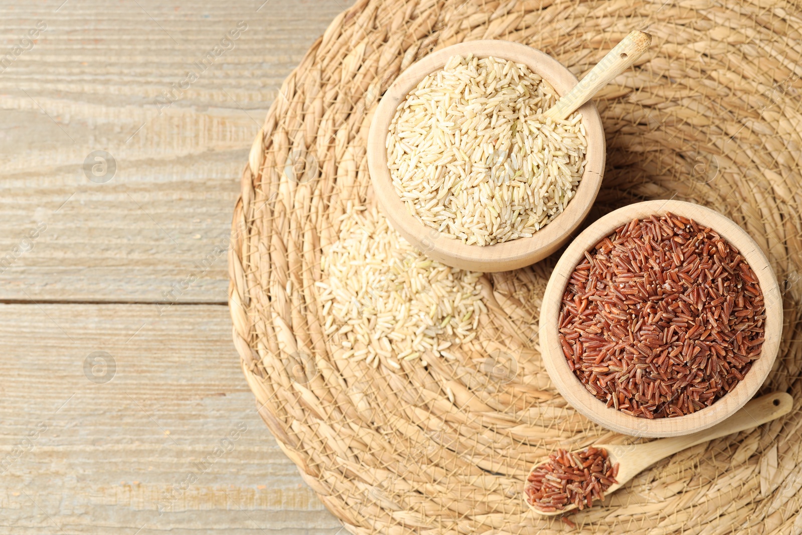 Photo of Different sorts of raw brown rice on wooden table, top view. Space for text