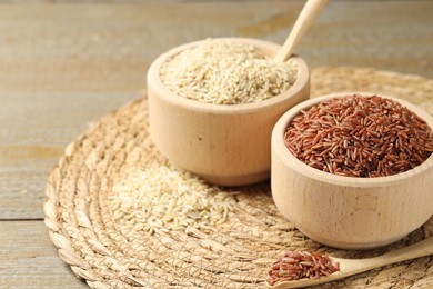 Photo of Different sorts of raw brown rice on wooden table, closeup