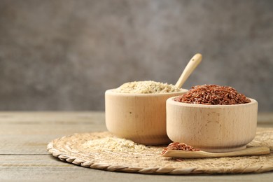 Photo of Different sorts of raw brown rice on wooden table against grey background, closeup. Space for text