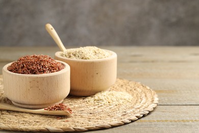 Photo of Different sorts of raw brown rice on wooden table against grey background, closeup. Space for text