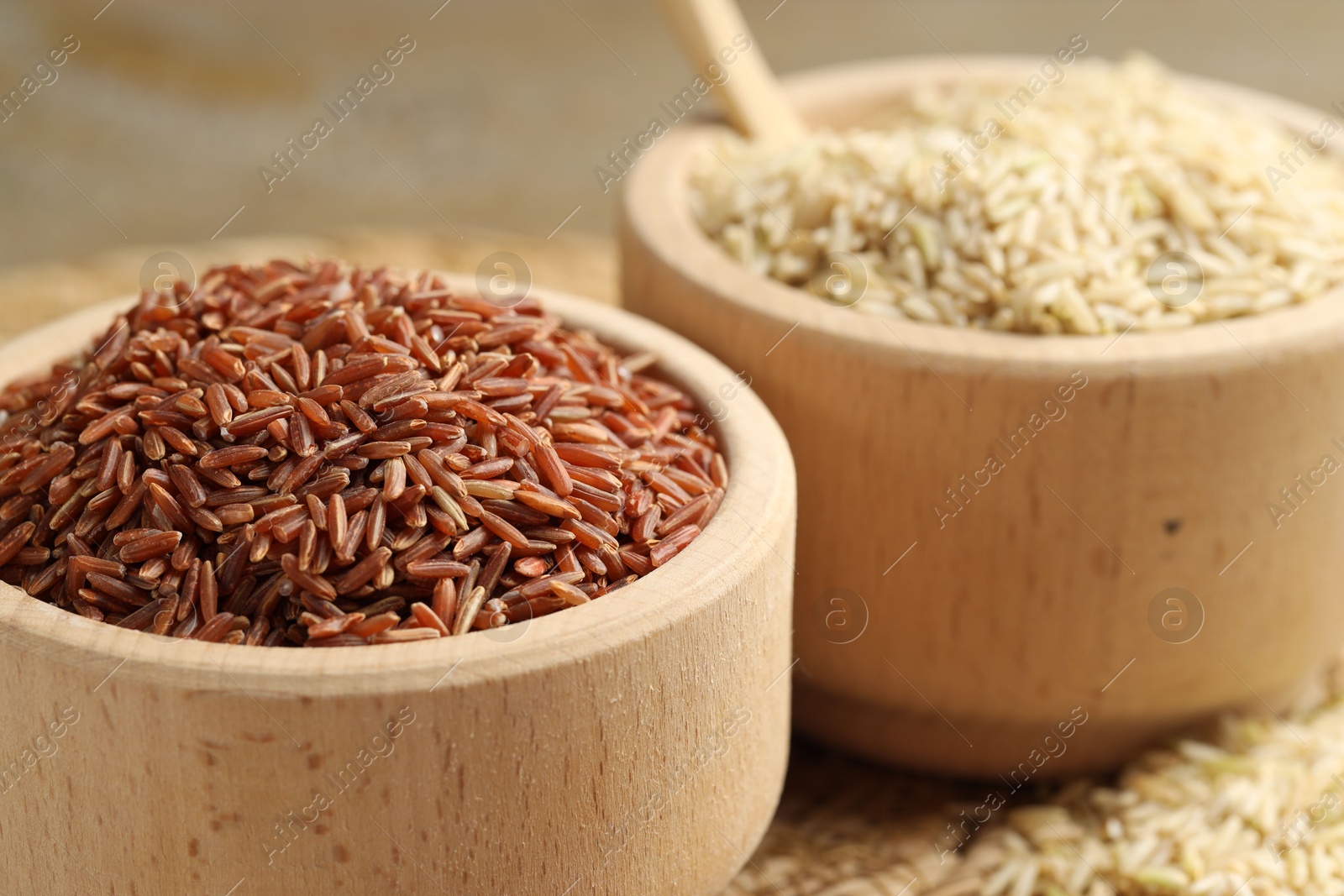 Photo of Different sorts of raw brown rice on table, closeup