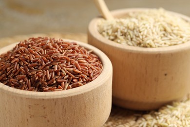 Photo of Different sorts of raw brown rice on table, closeup