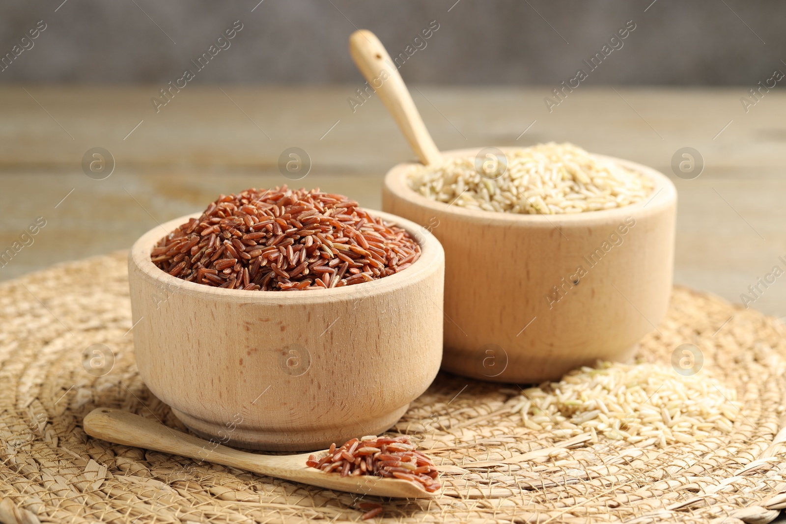 Photo of Different sorts of raw brown rice on table against grey background, closeup