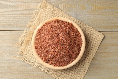 Photo of Raw brown rice in bowl on wooden table, top view