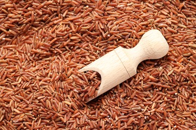 Photo of Pile of brown rice with wooden scoop, top view