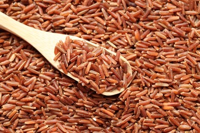 Photo of Pile of brown rice with wooden spoon, above view