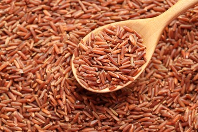 Photo of Brown rice in wooden spoon over pile of grains, above view