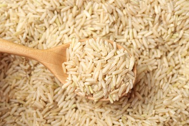 Photo of Pile of brown rice with wooden spoon, top view