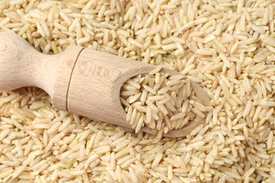 Photo of Pile of brown rice with wooden scoop, top view