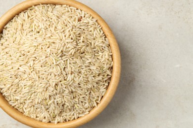 Photo of Brown rice in bowl on light grey table, top view. Space for text