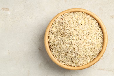 Photo of Brown rice in bowl on light grey table, top view. Space for text