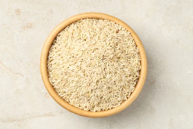 Photo of Brown rice in bowl on light grey table, top view