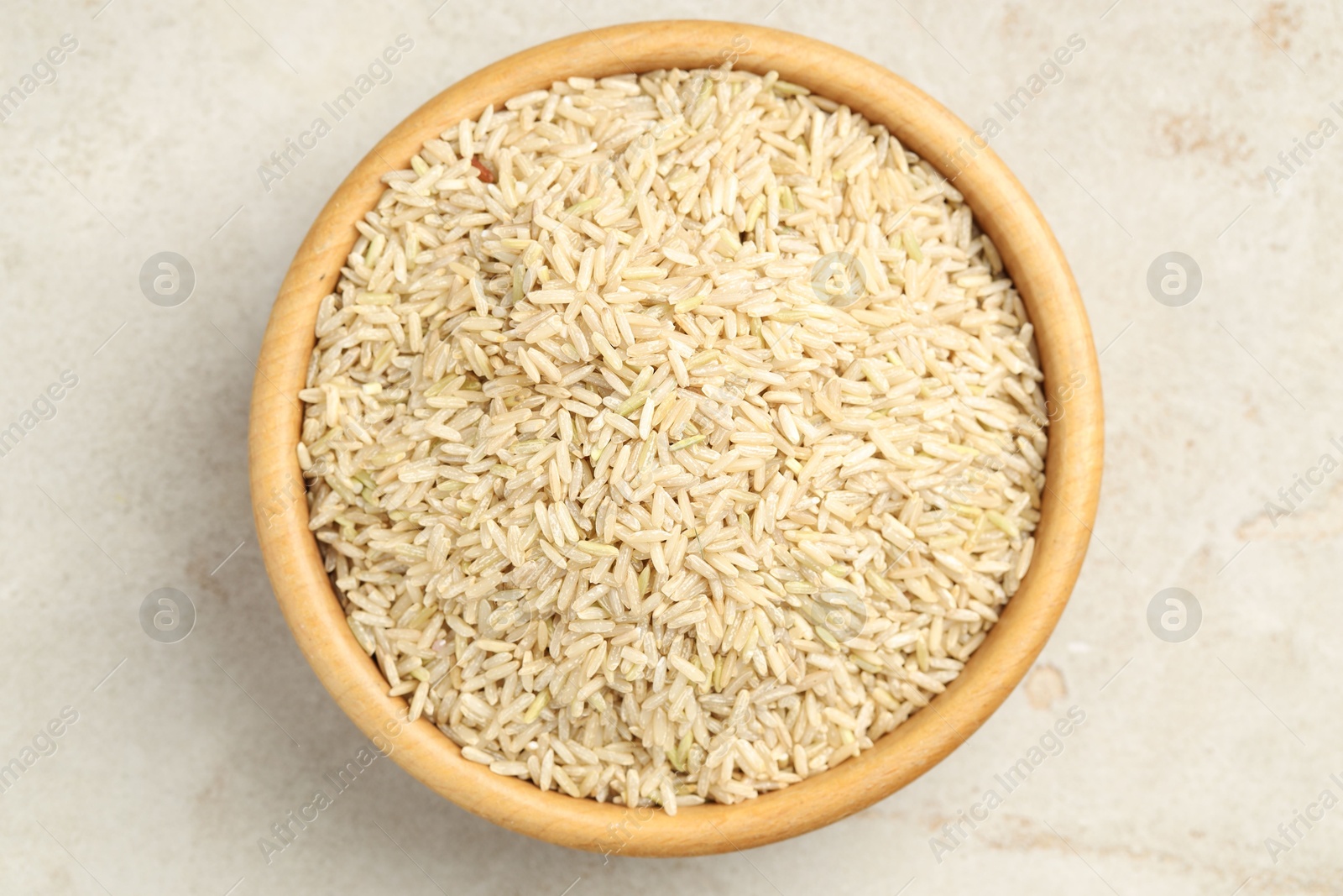 Photo of Brown rice in bowl on light grey table, top view