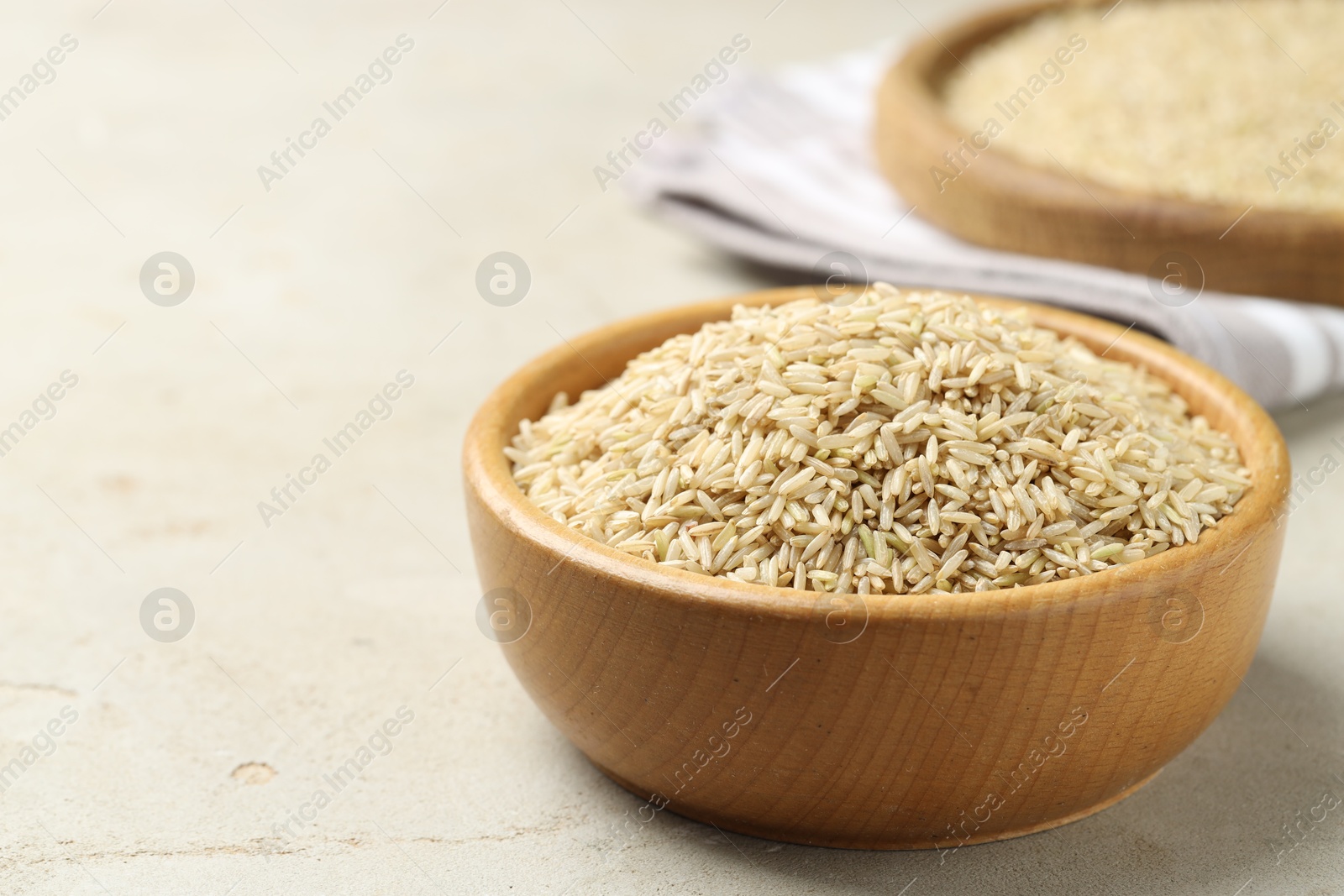 Photo of Brown rice in bowl on light grey table, closeup. Space for text