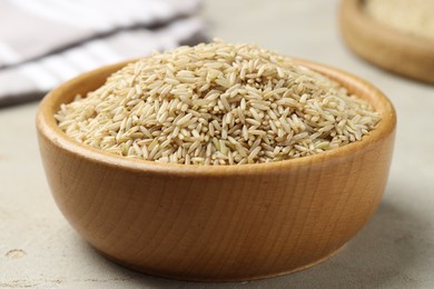 Photo of Brown rice in bowl on light grey table, closeup