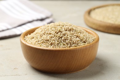 Photo of Brown rice in bowl on light grey table, closeup