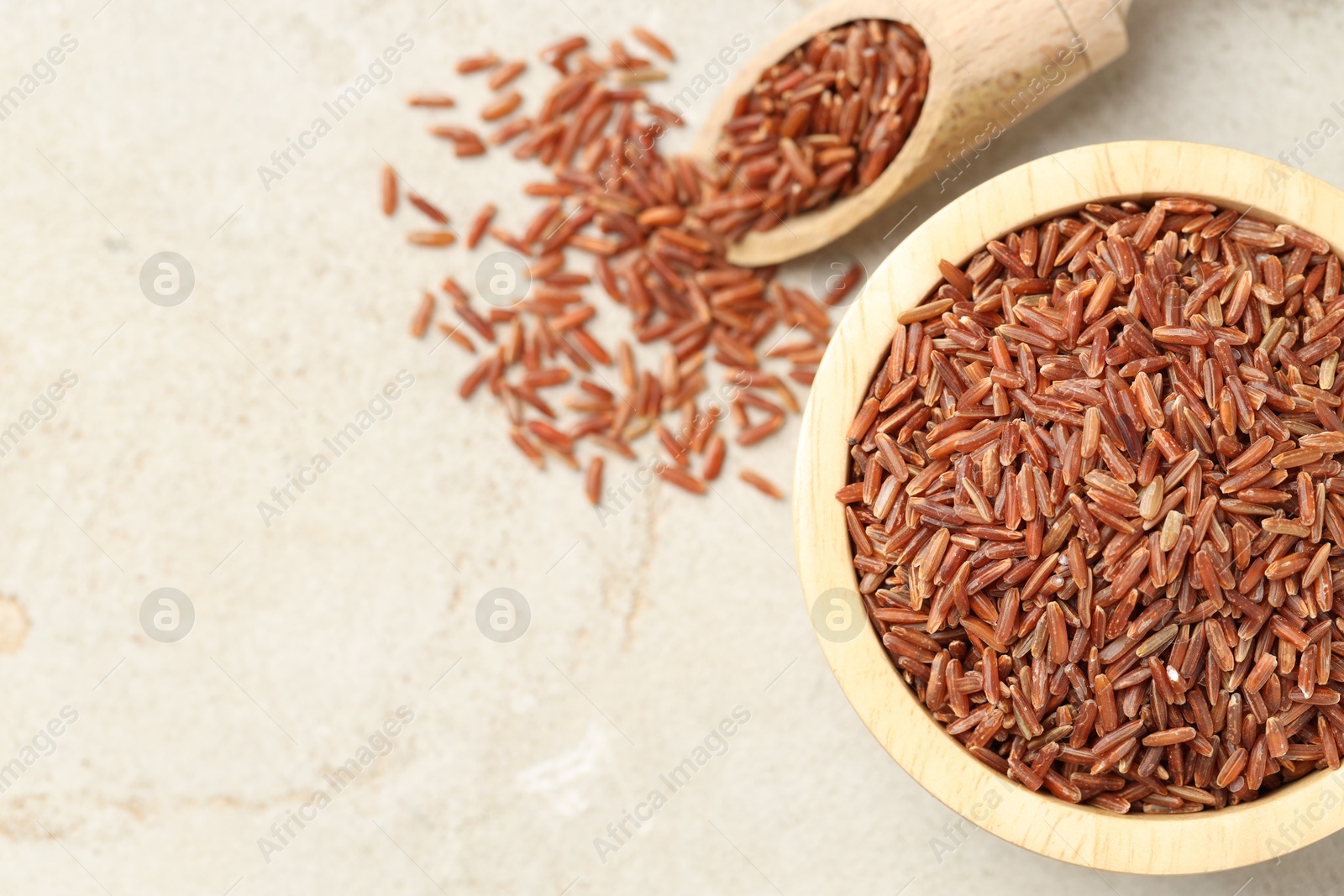 Photo of Brown rice in bowl and scoop on light grey table, flat lay. Space for text