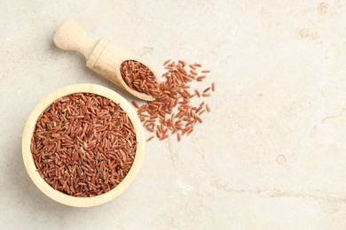 Photo of Brown rice in bowl and scoop on light grey table, flat lay. Space for text