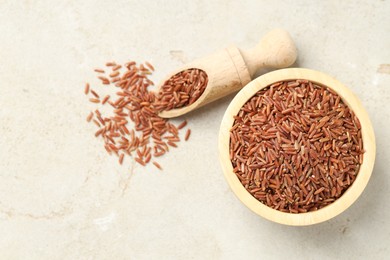 Photo of Brown rice in bowl and scoop on light grey table, flat lay. Space for text