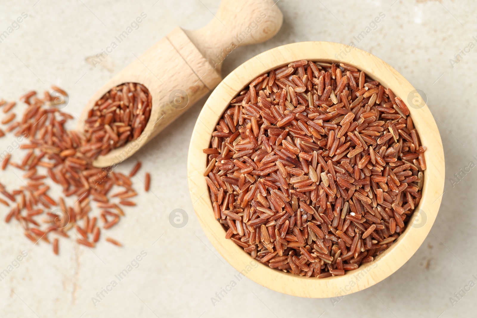 Photo of Brown rice in bowl and scoop on light grey table, flat lay