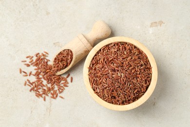 Photo of Brown rice in bowl and scoop on light grey table, flat lay