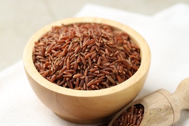 Photo of Brown rice in bowl and scoop on table, closeup