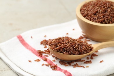 Photo of Brown rice in wooden spoon and bowl on table, closeup. Space for text