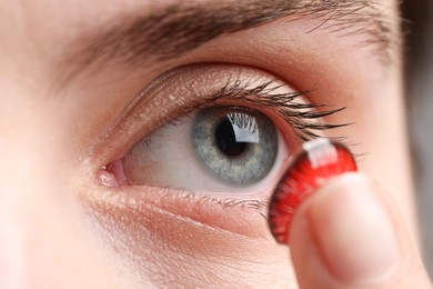 Photo of Woman putting in red color contact lens, closeup