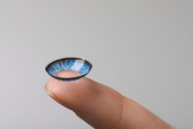 Photo of Woman with blue color contact lens on grey background, closeup