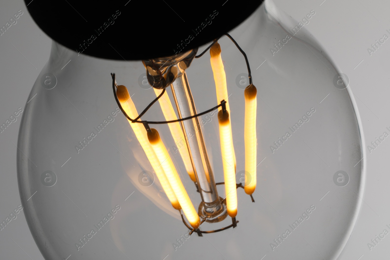 Photo of Glowing light bulb on grey background, closeup