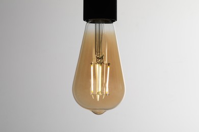 Photo of Glowing light bulb on grey background, closeup