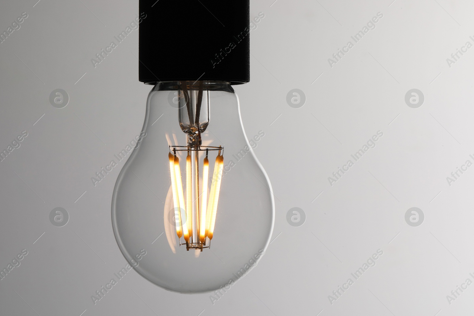 Photo of Glowing light bulb on grey background, closeup