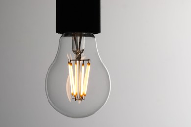 Photo of Glowing light bulb on grey background, closeup