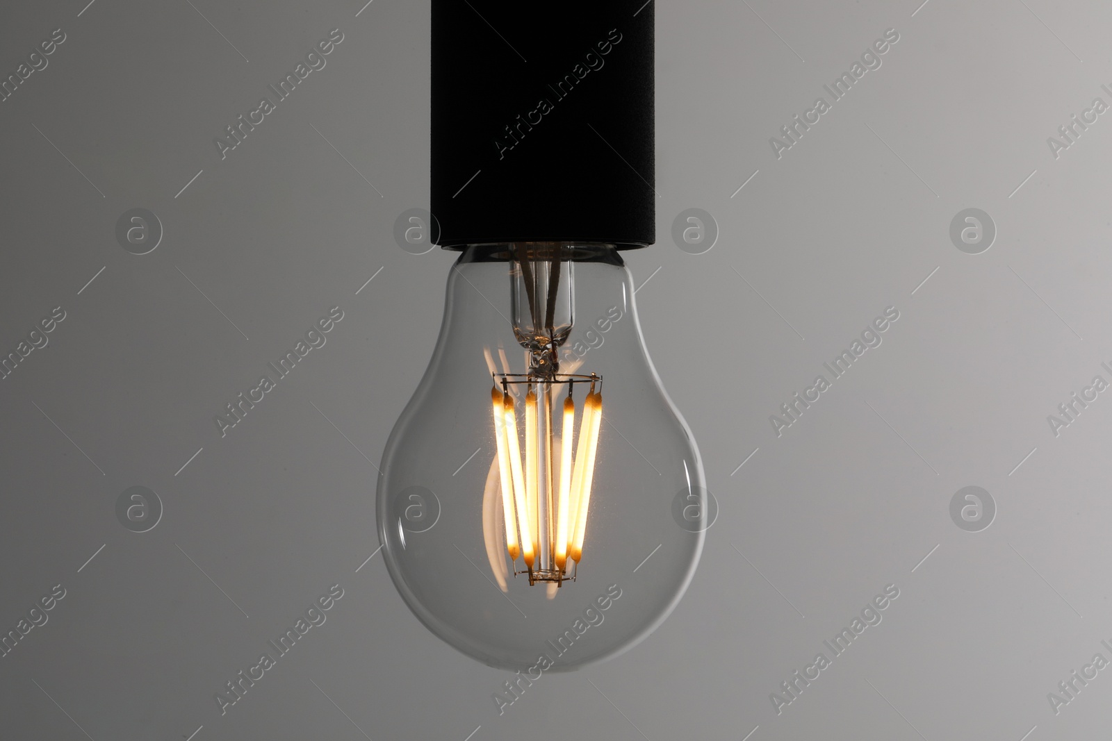 Photo of Glowing light bulb on grey background, closeup