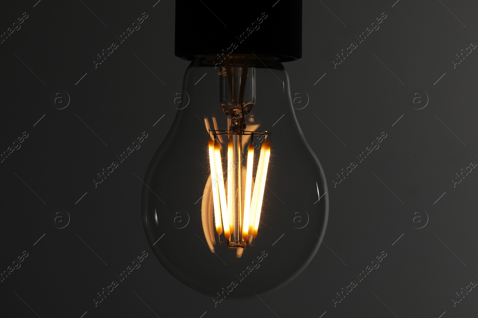 Photo of Glowing light bulb on grey background, closeup