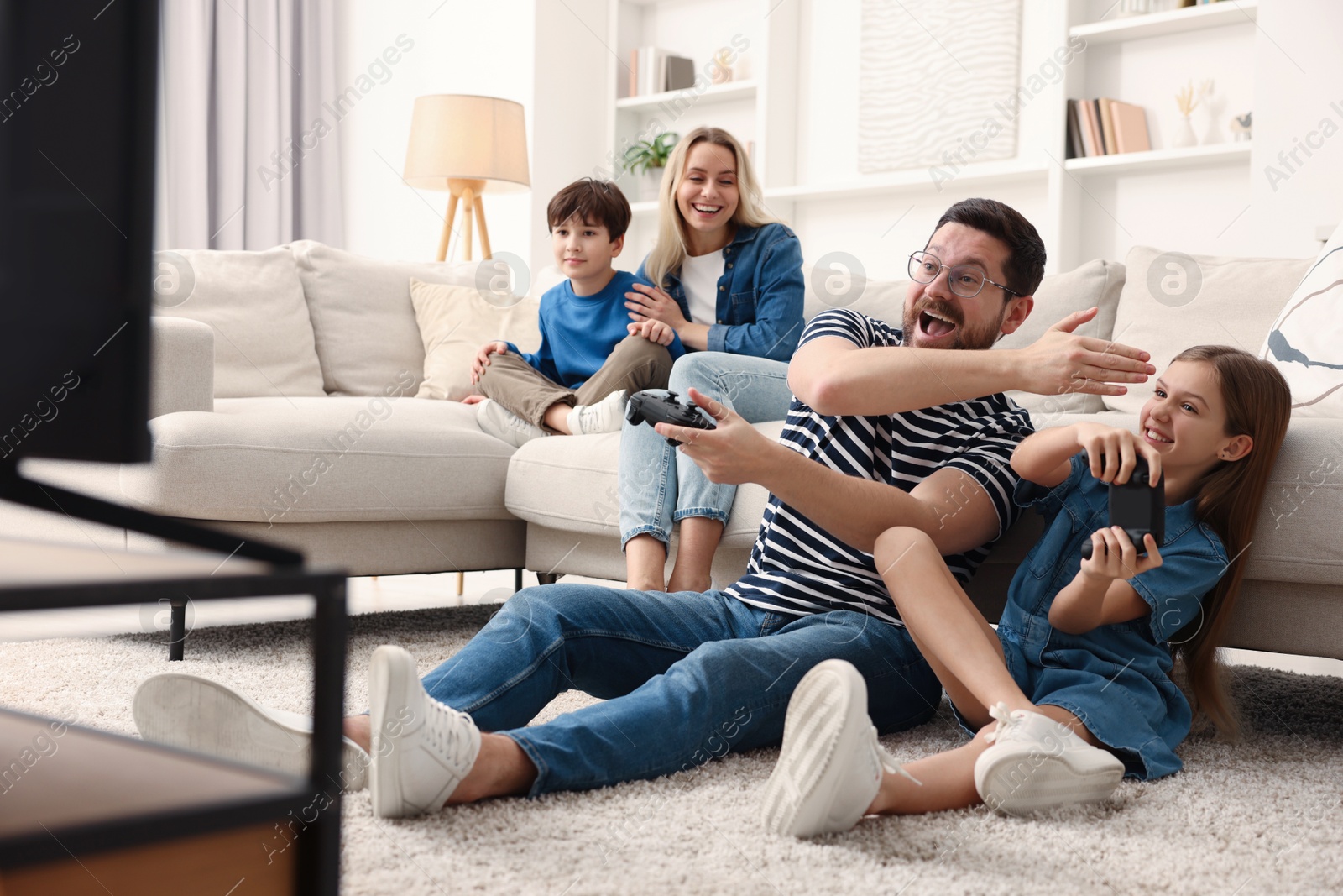 Photo of Happy family playing video games in living room