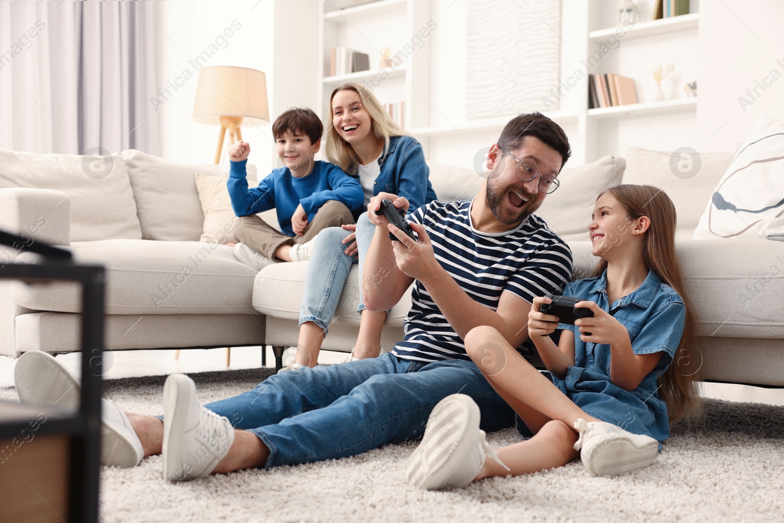 Photo of Happy family playing video games in living room