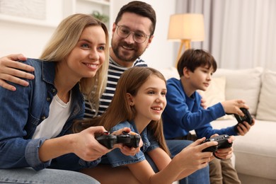 Photo of Happy family playing video games on sofa at home