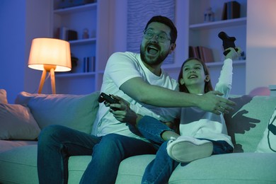 Photo of Happy father and his daughter playing video games on sofa in living room