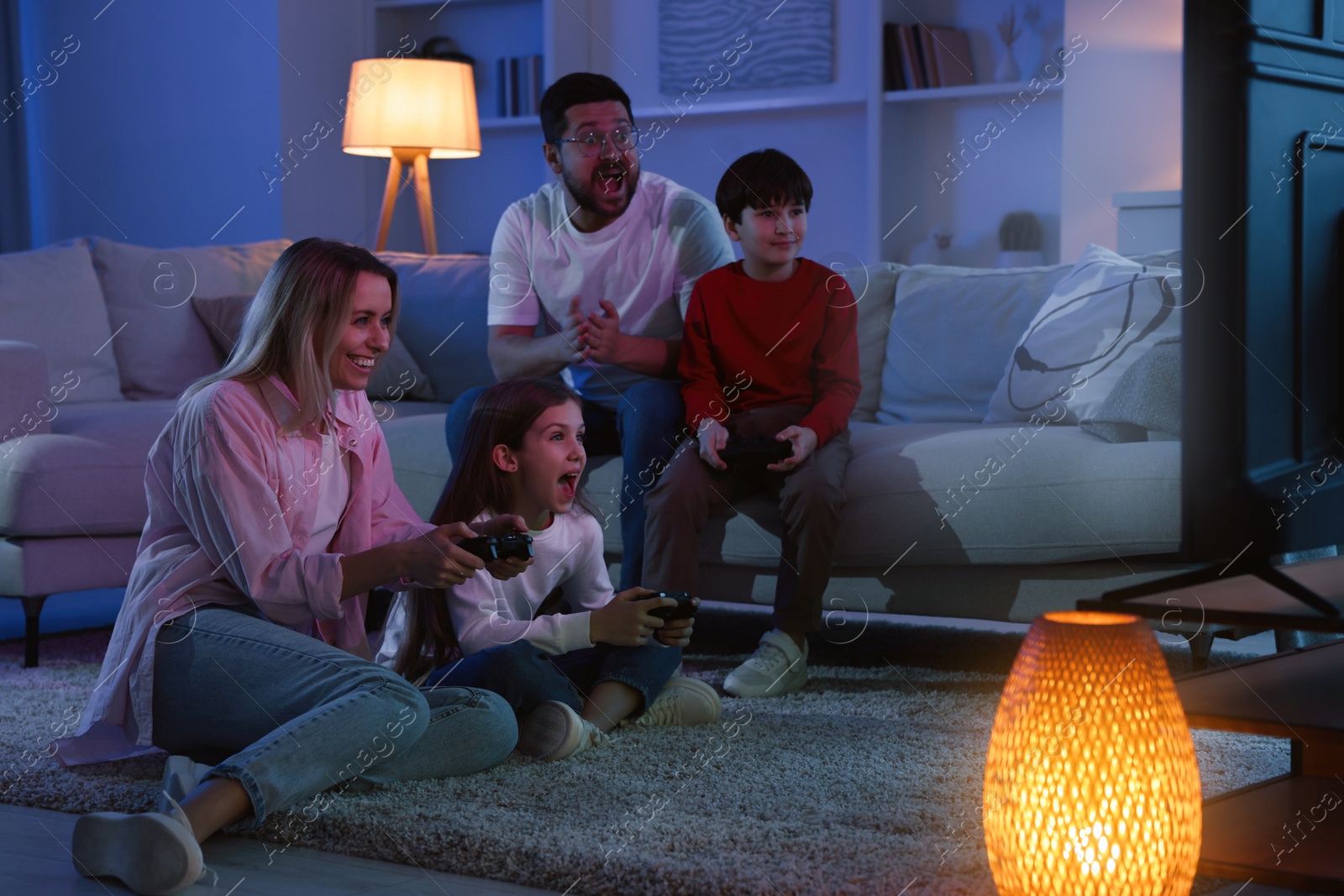 Photo of Happy family playing video games in living room at night