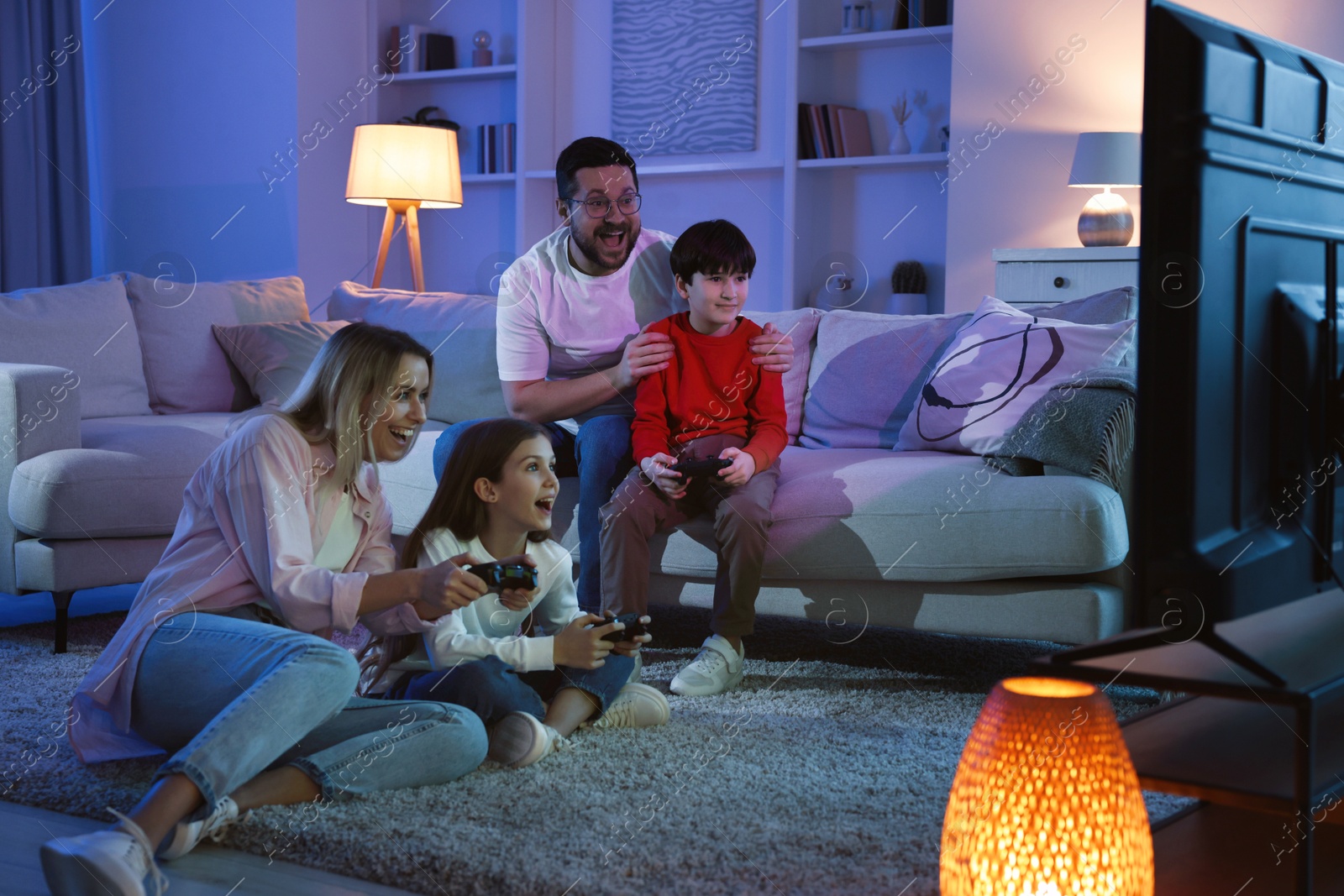 Photo of Happy family playing video games in living room at night