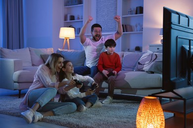 Photo of Happy family playing video games in living room at night