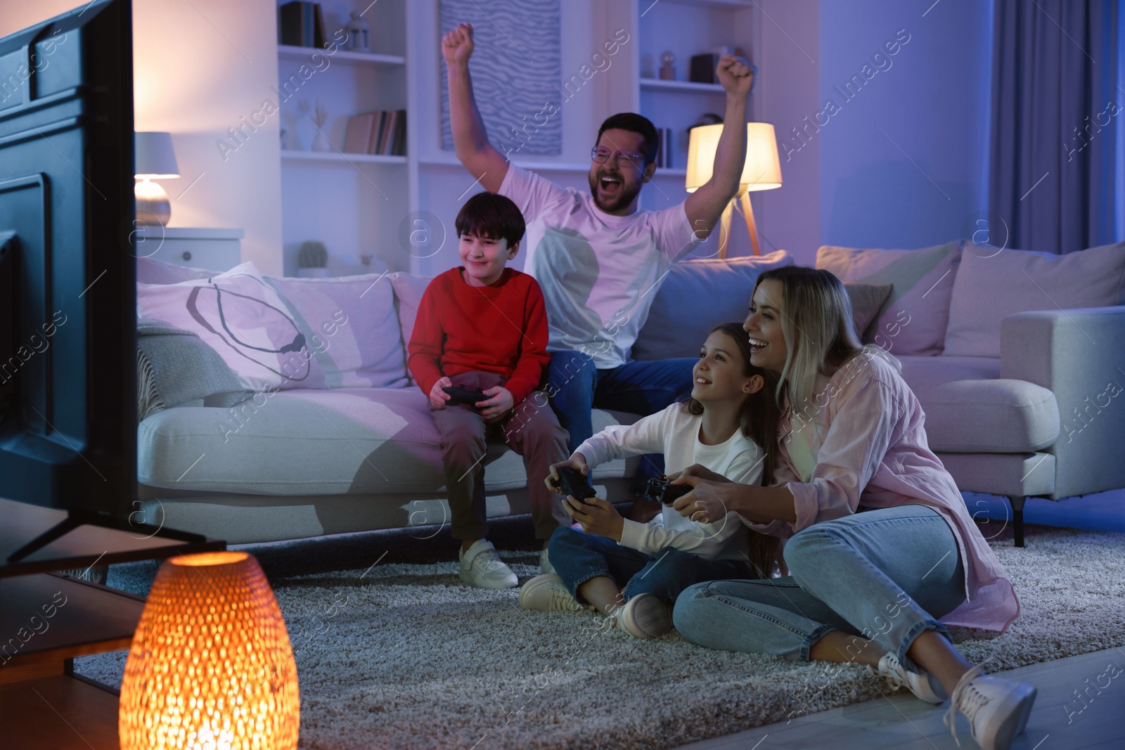 Photo of Happy family playing video games in living room at night