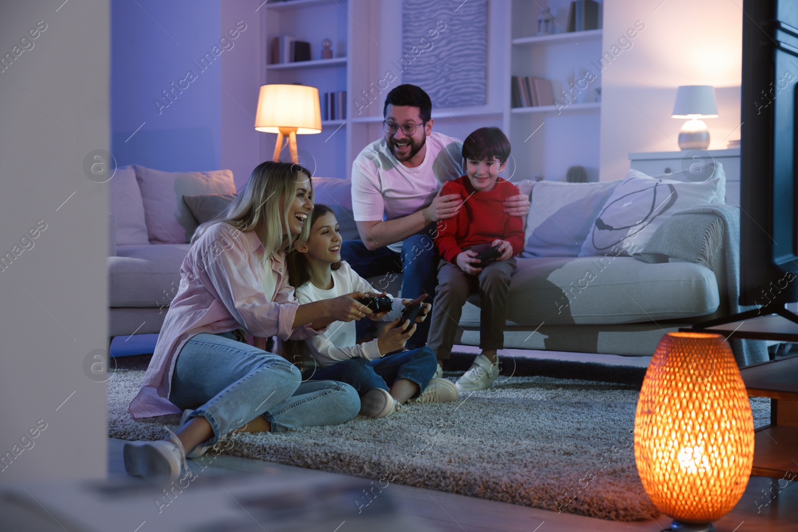 Photo of Happy family playing video games in living room at night