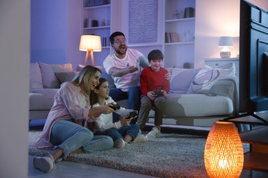 Photo of Happy family playing video games in living room at night