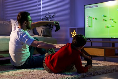 Photo of Father and his son playing video game on floor at home