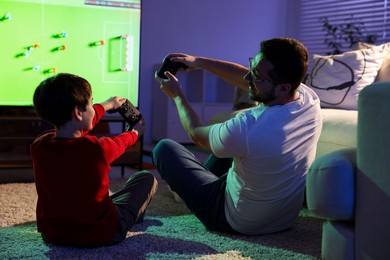 Photo of Father and his son playing video game on floor at home