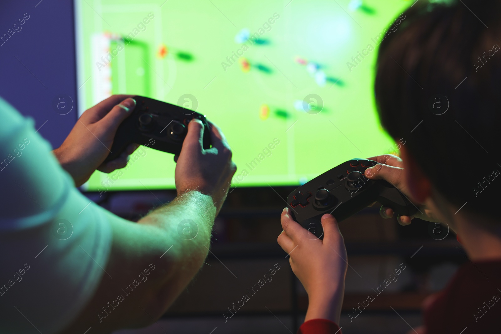 Photo of Father and his son playing video game at home, closeup