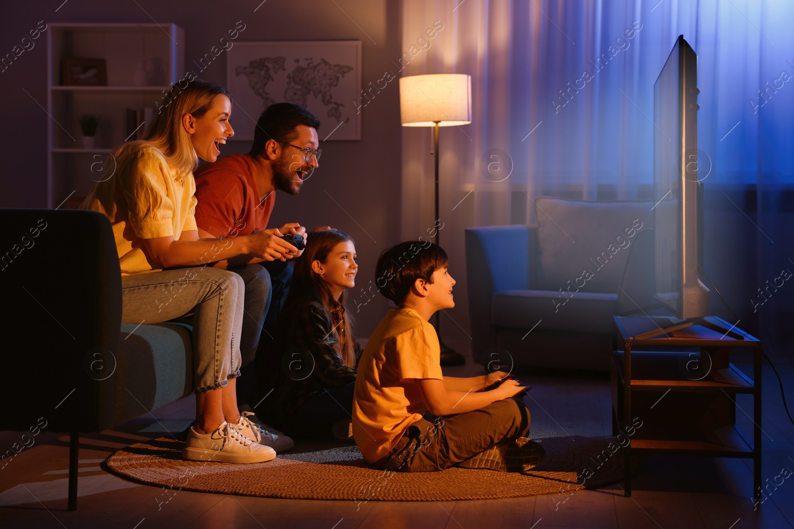 Photo of Happy family playing video games in living room at night